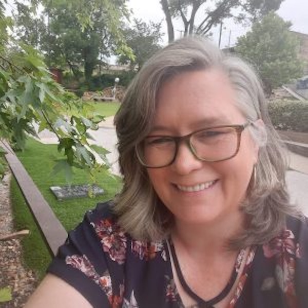 A smiling Helen Wade wearing glasses in the outdoors.
